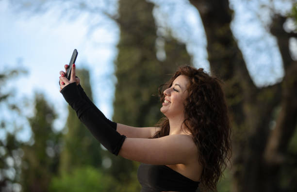 istock Curly haired woman is taking a selfie at public park. 1500740740