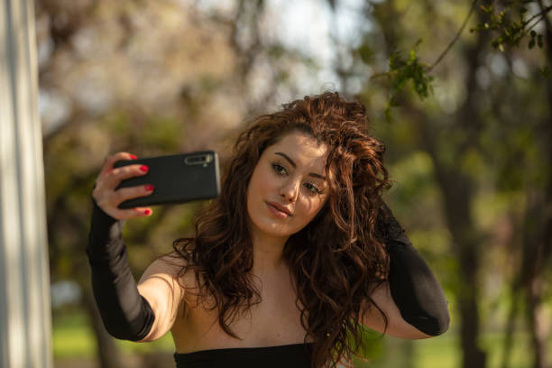 istock Curly haired woman is taking a selfie at public park. 1500740895