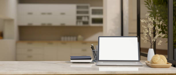 istock A laptop white screen mockup on a tabletop over blurred background of a modern kitchen. 1500742712