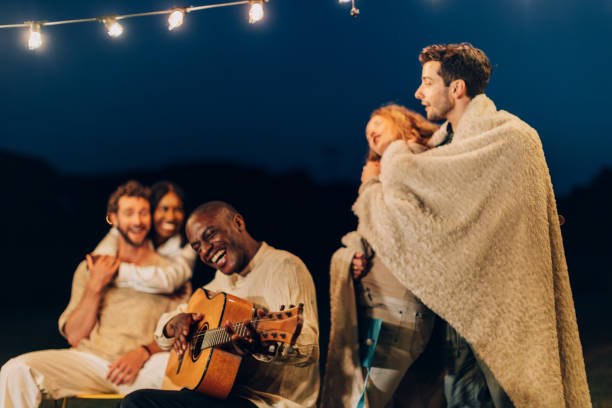 istock friends sing with guitar around the fire in a summer party 1500743003
