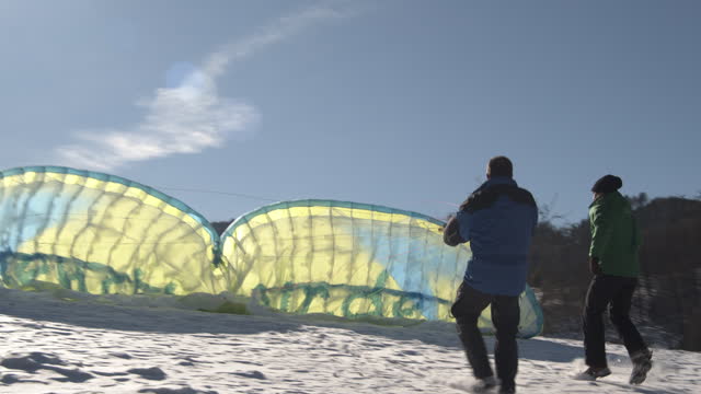 Two men prepping paraglider