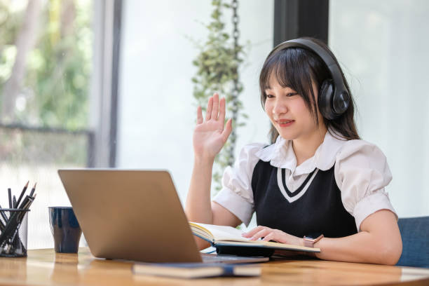 Smiling asian female student in headphone attending online lesson, watching education webinar on laptop. Smiling asian female student in headphone attending online lesson, watching education webinar on laptop. online tutors stock pictures, royalty-free photos & images