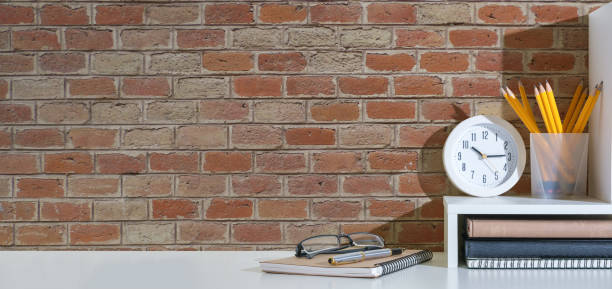 istock Stylish workspace with potted plant, books on white table against brick wall. 1500748411