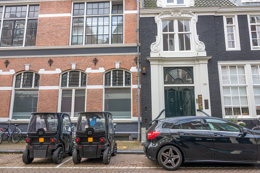 Netherlands, Amsterdam - September 26, 2021: Small cobbled street. Two mini cars are parked in front of the facade of authentic houses