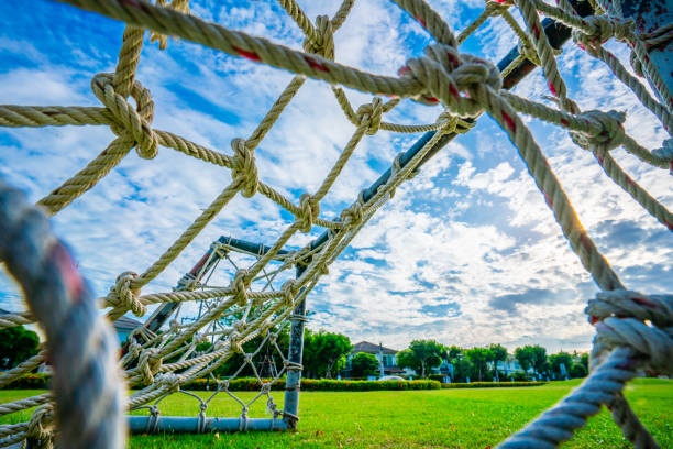 istock Rope net goal, mini soccer field with green grass Simple, old-fashioned miniature mosquito nets woven with straw clutter up the park sky and white clouds background, selective focus, soft focus. 1500753908