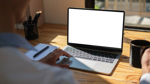 istock Over shoulder view of businessman using laptop computer in bright office. 1500760294