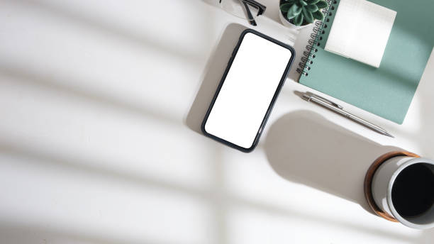 istock Flat lay, top view of smart phone, notebook and coffee cup on white table. Copy space for your text. 1500762458