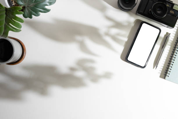 istock Flat lay image of modern workplace with smart phone, notebook, coffee cup and camera on white table. Copy space for your text. 1500762607