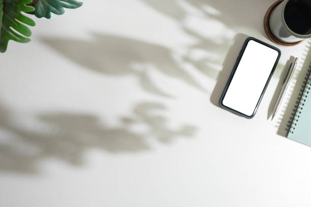 istock Modern workplace with smart phone, notebook and coffee cup  on white table. Top view with copy space. 1500762859