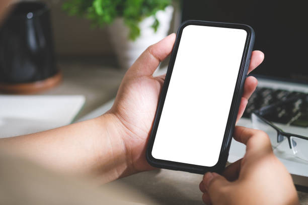 istock Over shoulder view of woman using mobile phone at her workplace. Blank screen for your advertise design. 1500764048