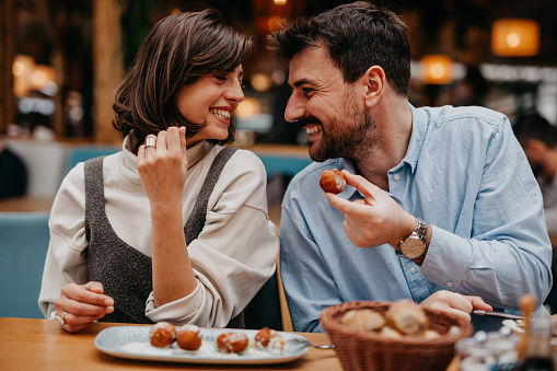 Photograph the two individuals engaging in conversation, smiling, or sharing a light-hearted moment while enjoying their meal