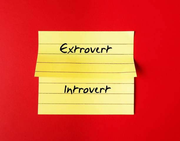 Yellow note stick on red background with handwritten text - INTROVERT EXTROVERT, different traits personalities - Introverts tend to feel drained after socializing while extroverts tend to feel energized nota amarilla sobre fondo rojo con texto escrito a mano - introvertido extrovertido, diferentes rasgos personalidades - los introvertidos tienden a sentirse agotados después de socializar, mientras que los extrovertidos tienden a sentirse energizados