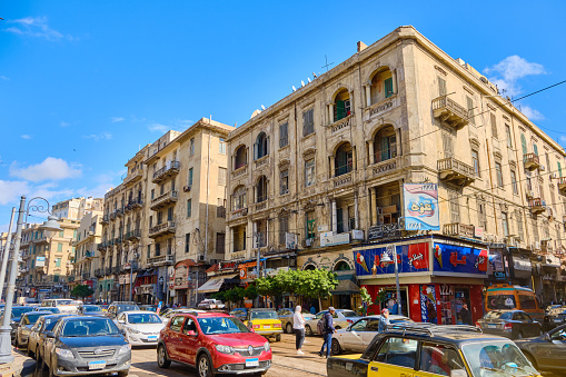 Cars and people on the street. British colonial architecture of Alexandria, Egypt, March 2023