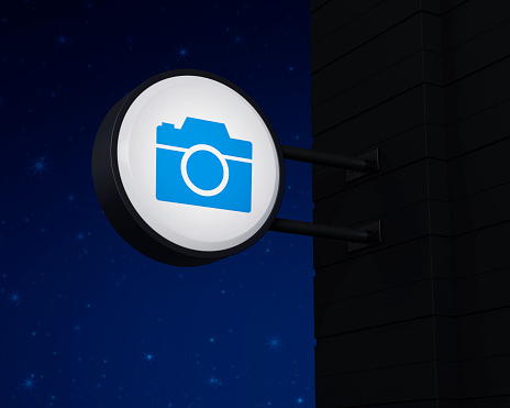 Camera icon on hanging black rounded signboard over fantasy night sky, Business camera service concept, 3D rendering