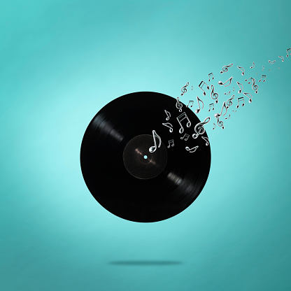 Close-up of blank LP vinyl record in mid-air with flying musical notes against light blue background.
