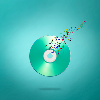 Close-up of blank music CD in mid-air with flying musical notes against light blue background.