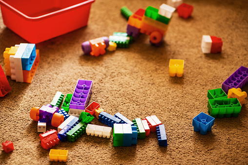 Children's plastic building blocks scattered on the floor in the room. The room is in disarray. Rtx, text place, happy childhood. Cozy house with comfortable atmosphere. Child development