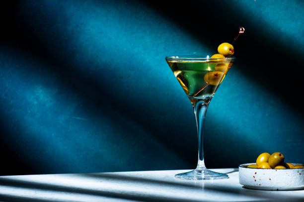 vodka martini con olive, cocktail drink alcolico con vodka e vermout, sfondo verde scuro, motivo di luci e ombre dure e luminose, spazio di copia - cocktail transparent cocktail shaker glass foto e immagini stock