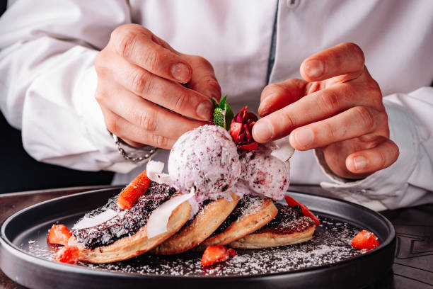 chef hand decorated pancakes with blueberry jam and ice cream