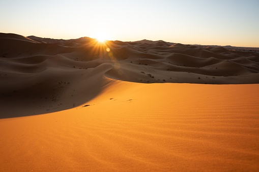 A breathtaking view of a desert landscape as the sun sets behind the horizon