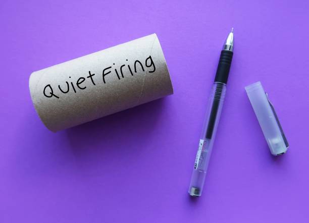 Purple toilet roll on purple background with handwriting text QUIET FIRING, act of nudging an employee out of the workplace, a constructive discharge which worker is essentially being forced to resign rollo de papel higiénico púrpura sobre fondo púrpura con texto escrito a mano despido silencioso, acto de empujar a un empleado fuera del lugar de trabajo, un despido constructivo que el trabajador esencialmente se ve obligado a renunciar