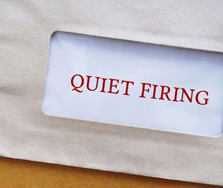 Office envelope with text QUIET FIRING, act of nudging an employee out of the workplace, a constructive discharge which worker is essentially being forced to resign by employers