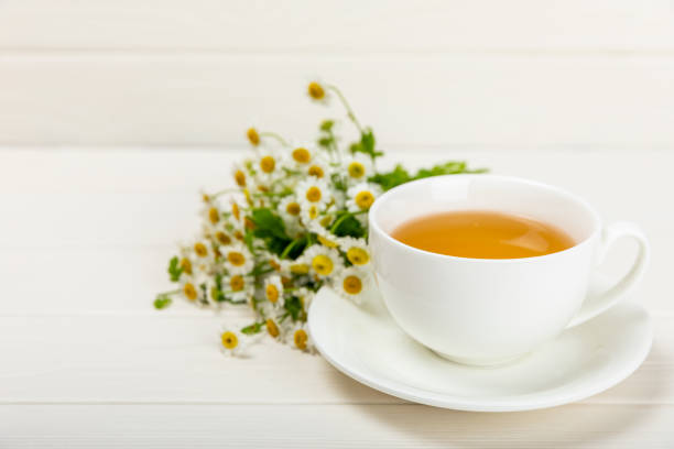 istock Chamomile tea in a cup on a white texture background. Natural hour with chamomile flowers. Herbal tea. Immunity tea.Natural healer concept. Healthy detox drink.Close up. Place for text. 1500808925