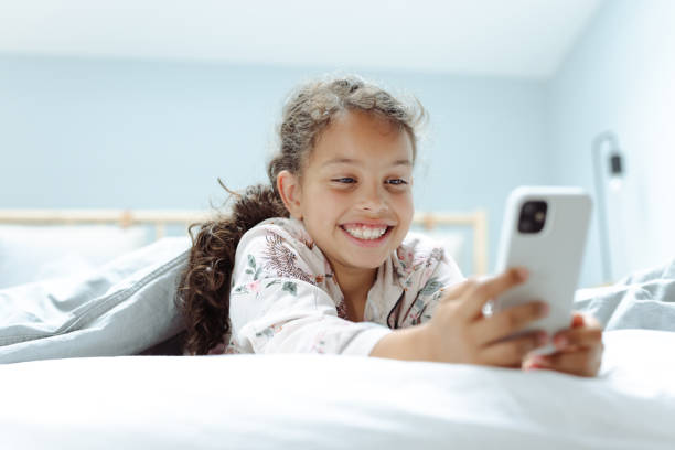 istock Happy girl using smart phone in bed. Digital native children 1500809253