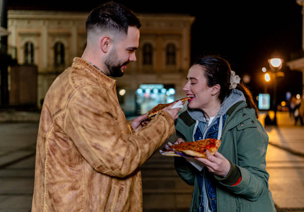 istock Young Couple Strolls Through the City while Savoring a Slice 1500809411