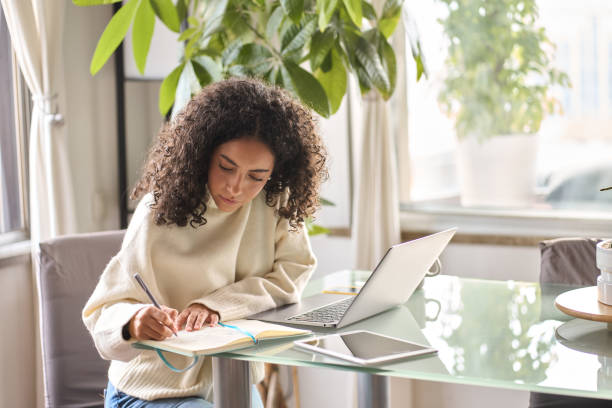 istock Young woman student using laptop watching online webinar writing at home. 1500809779