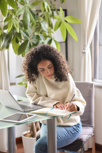 istock Young girl student using laptop watching online webinar writing at home. 1500809780