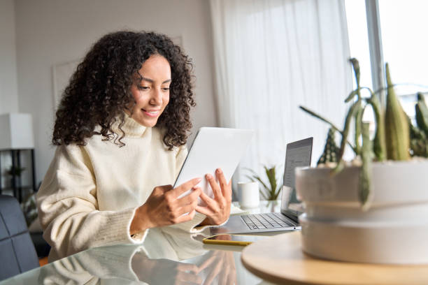 istock Young happy latin woman using digital tablet at home looking at tab. 1500809789