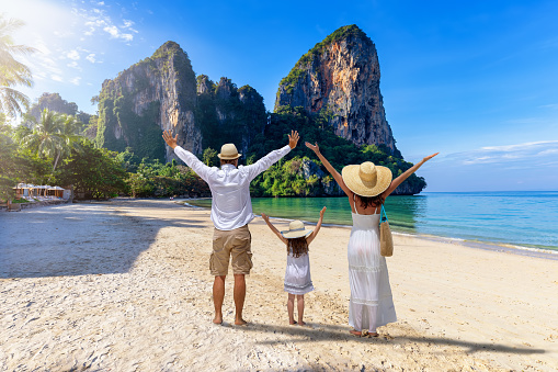 A happy family stands on the beautiful beach of Railay, Krabi, Thailand, during their summer vacations