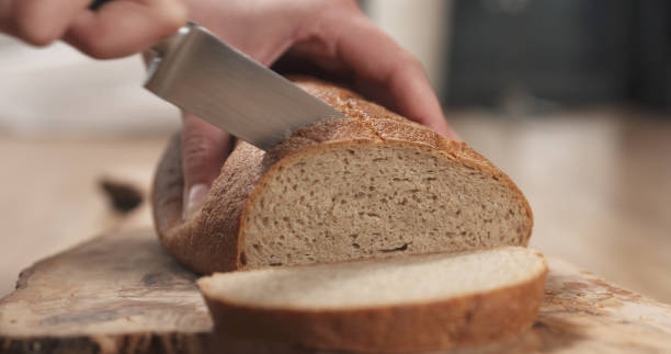 istock young female hands slicing rye wheat rustic bread on cutting board 1500814230