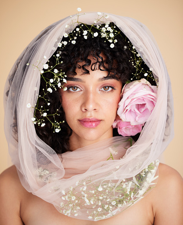 Veil, flowers and portrait of woman for beauty, cosmetics and makeup for wellness, glamour and glow in studio. Spring aesthetic, spa and serious face of girl for natural, skincare or facial treatment