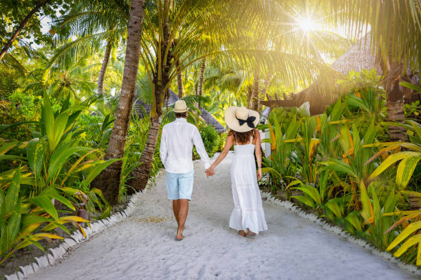 a luxury couple in white summer clothing walks on a tropical island - hotel tourist resort luxury tropical climate imagens e fotografias de stock