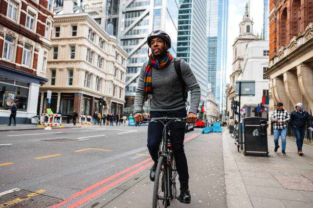 erwachsener schwarzer mann mit helm radelt zu seinem büro in der stadt - london england on the move commuter rush hour stock-fotos und bilder