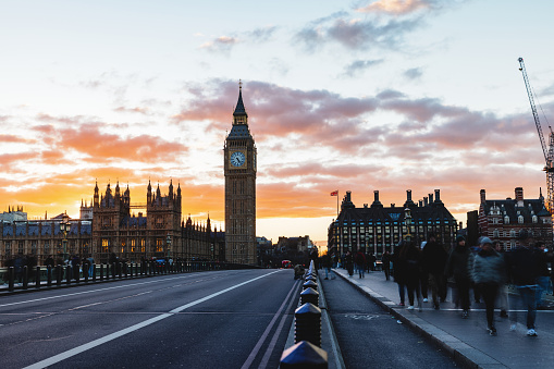 Beautiful view of Big Ben in London from the famous Westminster Bridge as the sun has set. The sky is colorful. The bridge is empty.