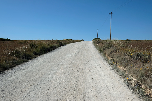 Empty road with a power line and some poles next to it in a rural area in Portugal
