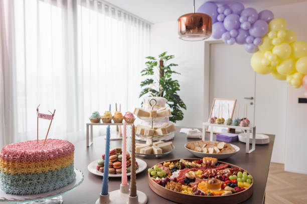 Cute baby shower decorations and delicious sweets, desserts, and snacks on a dining table before a baby shower. Aesthetic baby shower party with colorful and fun decorations at a bright modern apartment.