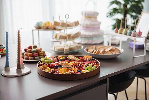 Delicious charcuterie boards, snacks, and desserts on a table before a gender reveal party in a bright modern apartment.