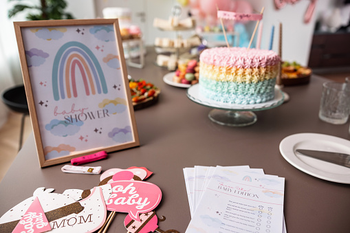 Decorated table for a baby shower celebration at a modern apartment. The table is full of various delicious snacks, sweets, desserts and decorations. vibrant and aesthetic baby shower party. No people.
