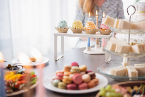 A wide variety of delicious sweet and salty snacks on a table at a party. Beautifully set and decorated table at a baby shower celebration full of macaroons, cupcakes, fresh fruit and sandwiches.