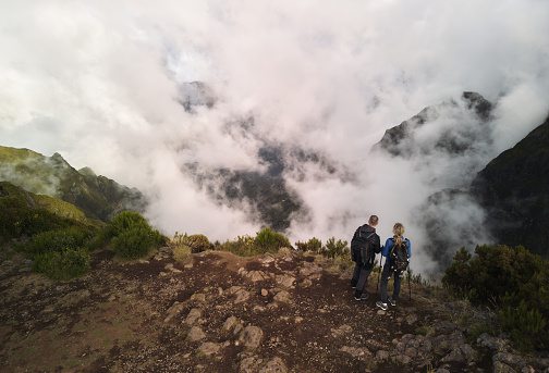 High angle view of a couple of hikers from the back standing on a mountain and looking at view.