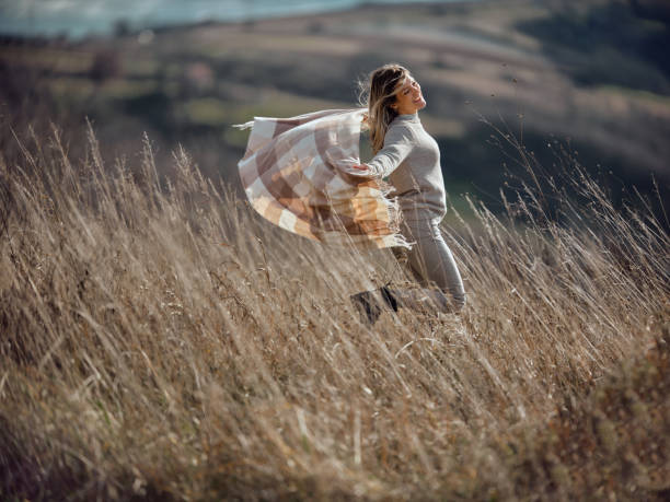 istock Playful woman having fun in tall grass on a hill. 1500820754