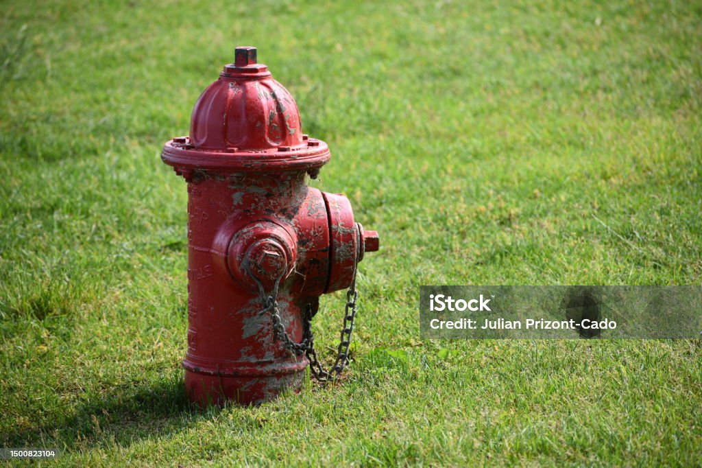 Red Worn Fire Hydrant in Urban Neighborhood Park Grass Fire Hydrant Stock Photo