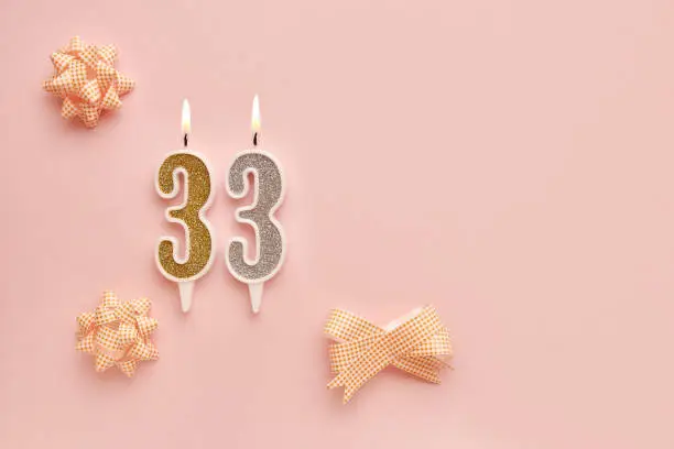 Number 33 on a pastel pink background with festive decorations. Happy birthday candles. The concept of celebrating a birthday, anniversary, important date, holiday. Copy space. banner