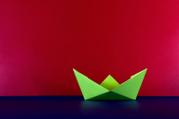 Yellow paper origami boat on a blue base and red background