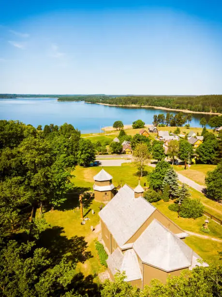 Photo of Aerial panning view beautiful iconic St.Joseph wooden stave church with no nails in famous Lithuania countryside holiday Village Paluse with Lusiai lake panorama in summer