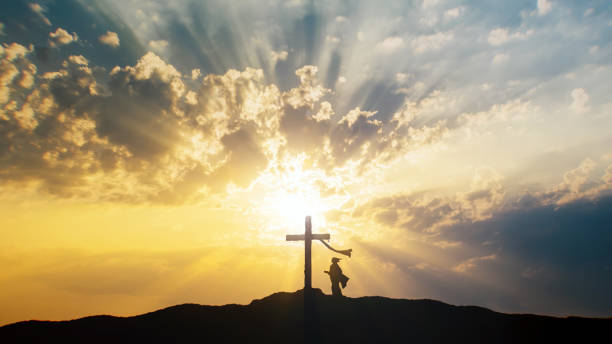 istock Woman silhouette praying at Cross - light sky 1500825436